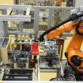 Potideckelmontage, orangener Roboterarm in der Anlage von oben