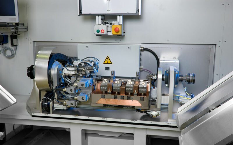 Laserheften Maschine mit Bronze-Platten, roter großer Knopf auf gelbem Hintergrund, viele Metallplatten schräg