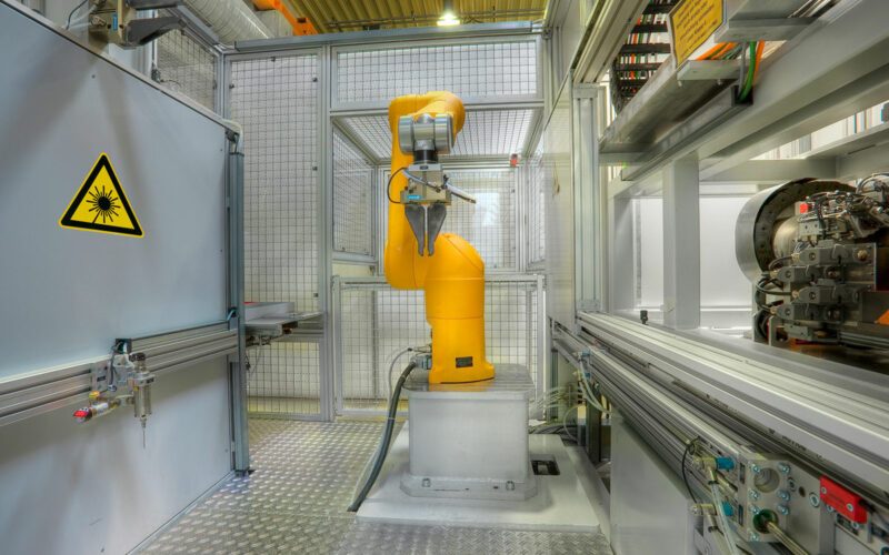 Laserheften, Maschine von innen, gelber Roboterarm in der Mitte