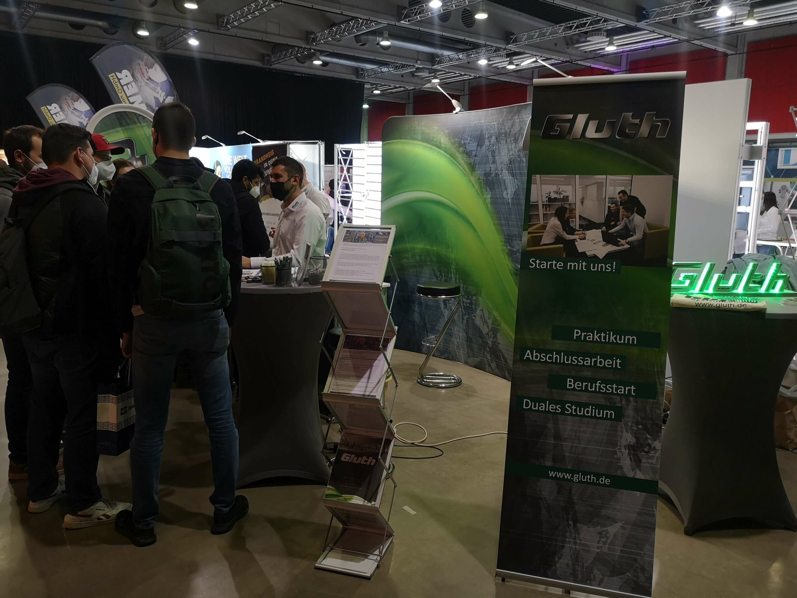 Firstcontact Messe in Deggendorf, Messestand der Gluth GmbH, viele interessierte Schüler stehen vor dem Stand