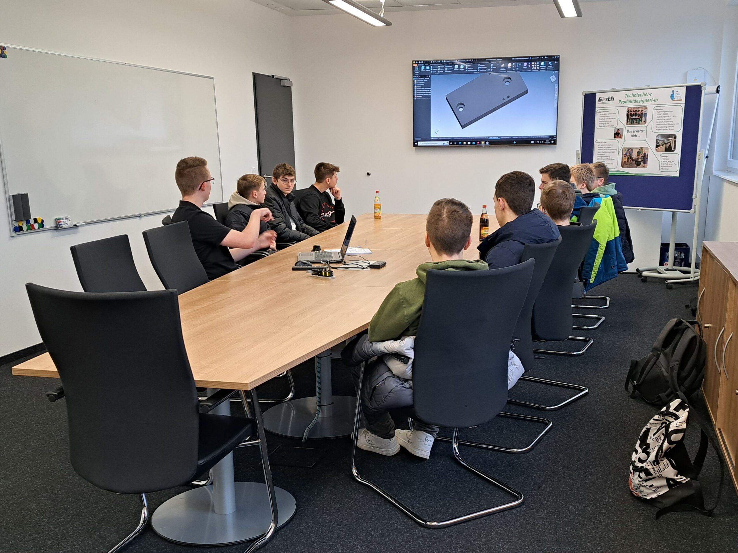 Ludmilla Realschule Bogen zu Besuch bei Gluth, Jugendliche sitzen an einem Tisch in einem Besprechungsraum und sehen sich etwas auf einem Bildschirm an