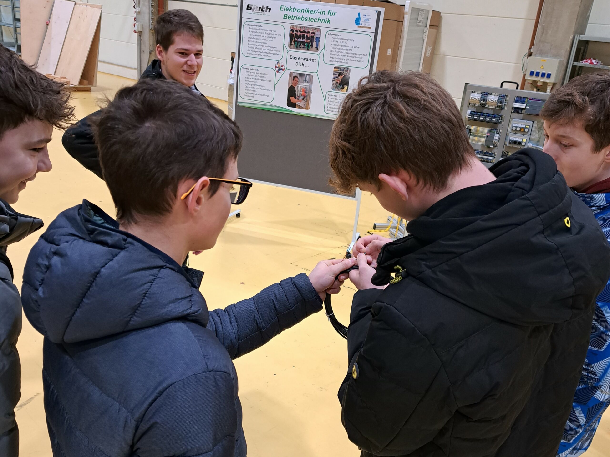 Ludmilla Realschule Bogen zu Besuch bei Gluth, 5 Jugendliche sehen sich ein Kabel an, zwei Jungs halten das Kabel