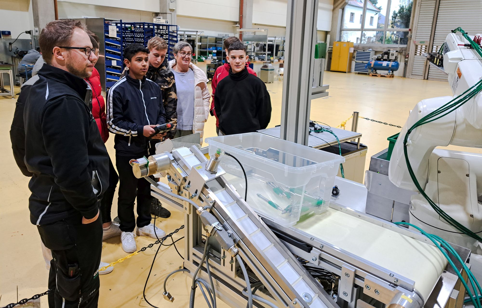 Mittelschule St. Stephan zu Besuch bei Gluth, interessierte Jugendliche vor einer Anlage, ein Junge steuert das Gerät